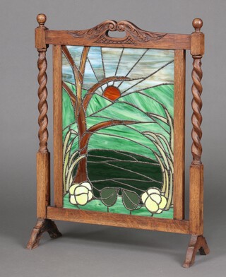 A 1930's oak fire screen, the centre with lead glazed panel depicting sunburst 81cm h x 64cm w x 22cm 