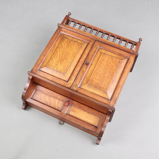 An Edwardian wall cabinet with bobbin turned gallery, fitted a shelf enclosed by a panelled door above cupboard enclosed by fall front 55cm h x 44cm w x 18cm d  