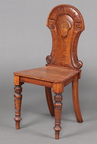 A Victorian carved oak hall chair with solid seat, raised on turned supports 