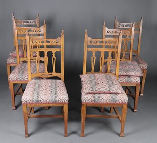A set of 6 oak Arts and Crafts bar back dining chairs with pierced bar backs and over stuffed seats, raised on square tapered supports with H framed stretcher  