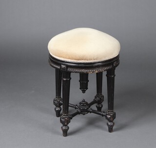 A Victorian ebonised revolving piano stool with mushroom coloured upholstered seat, raised on turned and fluted supports with X framed stretcher 