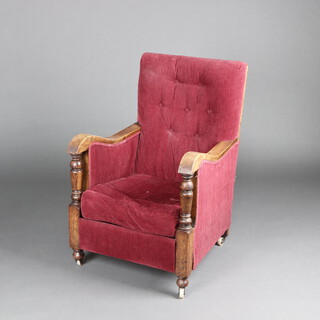 A 1930's oak show frame armchair upholstered in red material, raised on later casters 