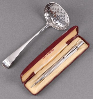 A Georgian oval silver fiddle pattern sifter spoon, with armorial decoration, London 1822 by William Eaton, 35g together with a silver cased Yard o'led propelling pencil  23g gross 