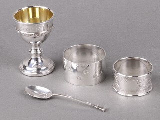 A silver egg cup with Celtic design Birmingham 1959, a silver napkin ring Sheffield 1978, 1 other napkin ring and a silver spoon, 133g 