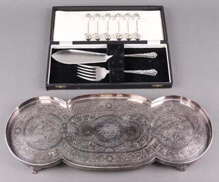 A shaped silver parted tea tray on panelled supports, a pair of silver plated fish servers case and 6 silver plated knife rests