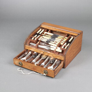 An 82 piece canteen of silver plated Old English pattern flatware comprising 4 serving spoons, 12 soup spoons, 12 dinner forks, 12 pudding forks, 12 pudding spoons, 6 teaspoons, carving knife, fork, 9 tea knives, 12 pudding knives, with simulated ivory handles, contained in an oak canteen box with tambour shutter  