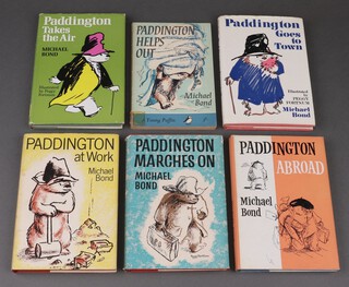 Bond, Michael, a collection of mainly first edition (some later) Paddington volumes to include, "Paddington Marches On" 1st Ed. 1964,  "Paddington at Work" 1st Ed. 1966,  "Paddington Goes to Town" 1st Ed. 1968, "Paddington Takes The Air" 1st Ed. 1970,  Paddington Abroad" 3rd Imp. 1966 together with "Paddington Helps Out" paperback, all with dust covers except paperback