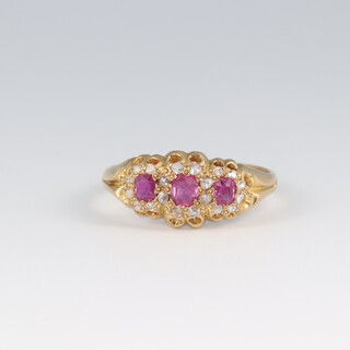 An 18ct gold 3 stone ruby and diamond surround dress, size O, 2.9g