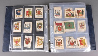 A large collection of Kensitas and other silks in a binder to include a large Union Jack, flags, tartans, ceramics, heraldry, medals