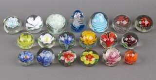 A collection of 19 floral decorated glass paperweights 