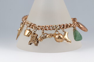 A yellow metal curb link charm bracelet with padlock clasp marked 9ct and 11 various charms, 18cm, 25.5 grams gross 