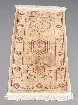 A pink ground Persian style machine made rug with 3 stylised medallions to the centre 178cm x 62cm (tear by fringe to 1 end) 