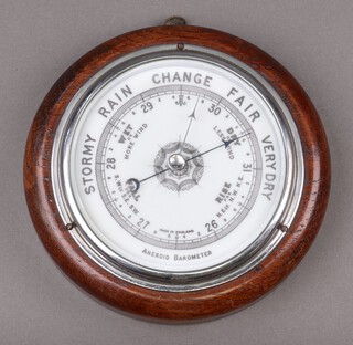An aneroid barometer with porcelain dial contained in an oak case 12cm diam.