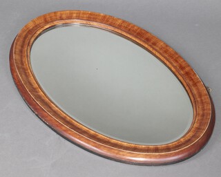 A 1930's oval bevelled plate wall mirror contained in a walnut frame 58cm x 86cm