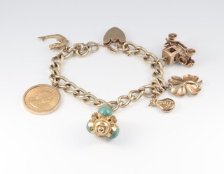 A 9ct gold curb link charm bracelet with padlock clasp,  hung an Elizabeth II 1957 sovereign, 5 9ct gold charms and a green hardstone set charm, gross weight 52g 