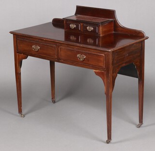 An Edwardian mahogany writing table, the raised back fitted 2 short drawers, the base fitted 2 long drawers, raised on square tapered supports, brass caps and casters 96cm h x 104cm w x 51cm d 