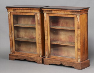 A pair of Victorian walnut ebonised and gilt mounted pier cabinets, fitted adjustable shelves enclosed by glazed panelled doors, raised on bracket feet 108cm h x 83cm w x 33cm d 