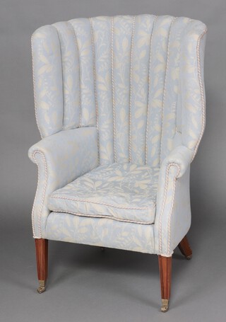 A 19th Century tub back armchair upholstered in blue and white floral material, raised on square tapered supports ending in brass caps and casters 