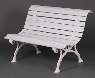 A Victorian garden bench with white painted cast iron ends and wooden slats 