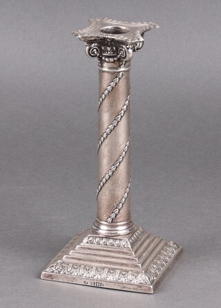 An Edwardian embossed weighted silver candlestick with Corinthian column capital and detachable sconce, on a square stepped base 20cm, London 1908 by William Hutton & Sons Ltd. London, base also marked The Goldsmiths & Company Newcastle 