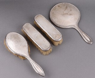 A 4 piece silver backed dressing table set with engine turned decoration, comprising hand mirror, hair brush and pair of clothes brushes, Birmingham 1919 