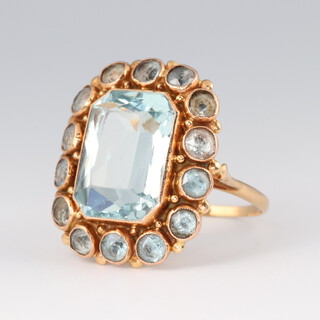 A gold testing as 14ct ring set a blue cushion shaped stone surrounded by circular cut stones, size Q