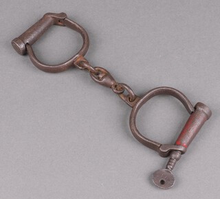 A pair of 19th Century iron handcuffs complete with key, no.95