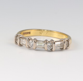 An 18ct yellow gold ring set 3 baguette cut diamonds supported by 4 circular cut diamonds, size N, 3.4g 