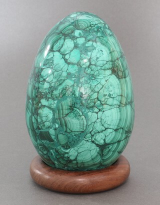 A green carved and polished malachite egg 12cm h x 5cm, on a hardwood stand 