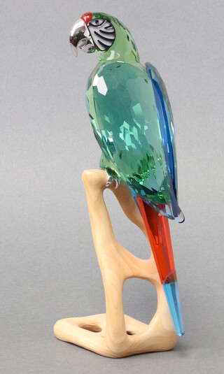 A Swarovski Crystal 2011 figure of a Macaw in chrome green on a wooden perch 22cm, boxed 