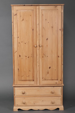 A pine wardrobe enclosed by panelled doors, the base fitted 2 drawers, on bracket feet 188cm h x 92cm w x 49cm d 