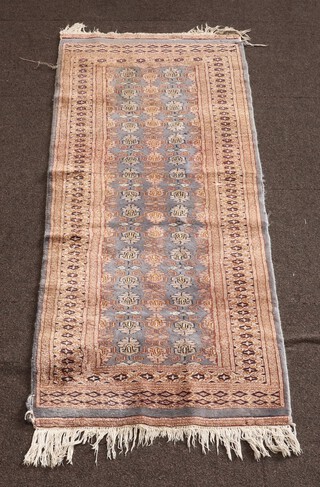 A blue and brown ground Bukhara runner with central floral medallion within a multi row border 184cm x 66cm (signs of old moth, damage in places)