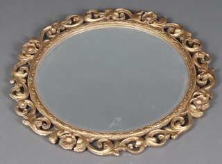 A circular bevelled plate mirror contained in a decorative pierced gilt plaster and wood frame 59cm 