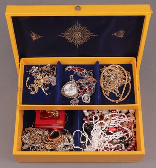 A quantity of costume jewellery including gold plated necklaces, beads, brooches, etc, contained in a yellow jewellery box 