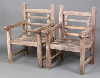 A pair of hardwood slatted garden armchairs 