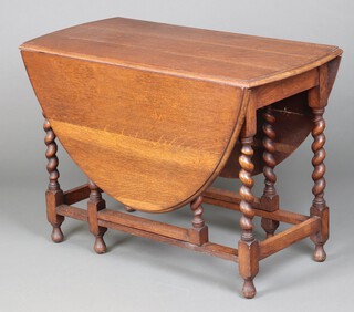 An oak drop flap dining table on spiral turned supports 74cm h  