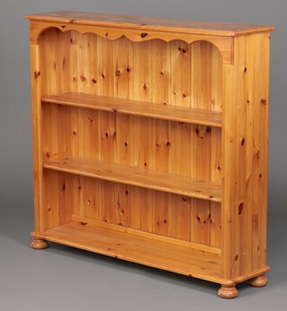 A pine 3 tier  bookcase fitted shelves, raised on bun feet 110cm h x 118cm w x 28cm d 