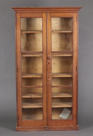 A Victorian pine cabinet with moulded cornice, fitted adjustable shelves enclosed by glazed panelled doors, raised on a platform base 183cm h x 103cm w x 37cm d 