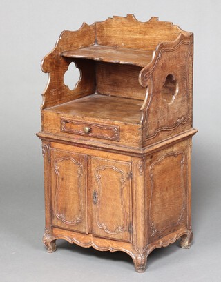 A 18th century style Continental carved oak bedside cabinet with 3/4 gallery above recess, the base fitted a drawer above cupboard enclosed by panelled doors 80cm h x 45cm w x 36cm d 