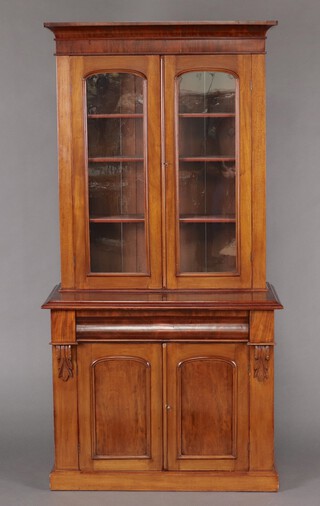 A Victorian mahogany bookcase on cabinet with moulded cornice, fitted adjustable shelves enclosed by arched panelled doors, the base fitted a drawer above cupboard enclosed by panelled doors, raised on a platform base 205cm h x 103cm w x 54cm d 