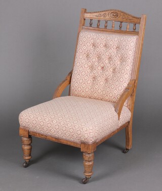 An Edwardian bleached mahogany nursing chair with carved spindle back 