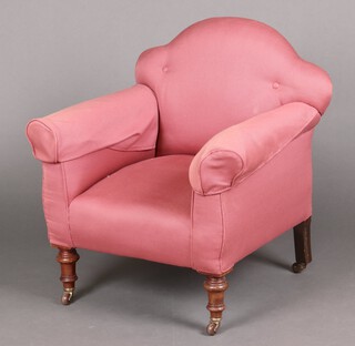 A Victorian armchair with arch shaped back, upholstered in pink material, raised on turned supports with ceramic casters 