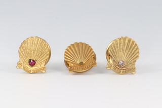 A gold fronted marked 10K dress stud in the form of the Shell motif to commemorate 10 years service 1.8g (without disc back), a 9ct gold ditto inset a diamond for 25 years service 2.2g (without back) and a gilt metal ditto inset a red stone for 15 years service (3)