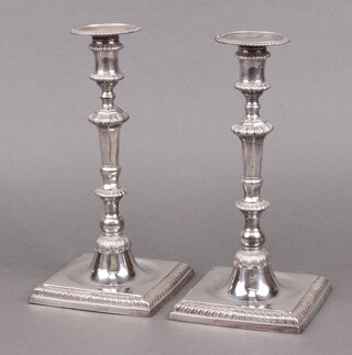 A pair of silver candlesticks on square bases with gadrooned decoration London 1967 by The Goldsmiths and Silversmiths Co., 24cm h, 1225 grams, together with 2 metal sconces 