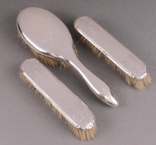 A plain silver backed hair brush Birmingham 1925 together with a pair of silver backed clothes brushes Birmingham 1924  