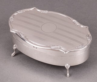 An oval silver trinket box with engine turned decoration, raised on hoof feet, Birmingham 1929, 5cm h x 13cm w x 8cm d 
