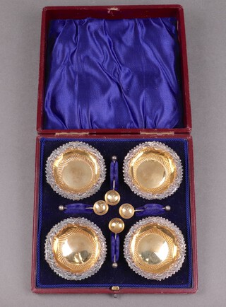 A set of 4 Victorian embossed circular silver salts with parcel gilt interiors and matching spoons, Birmingham 1897 by Miller Brothers, 36g, cased  