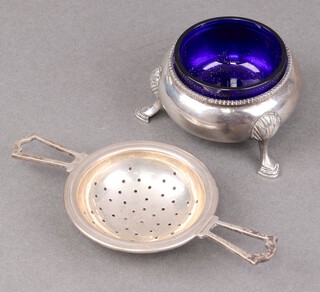 A Victorian silver salt with blue glass liner, London 1888 by William Evans together with a silver twin handed tea strainer Birmingham 1920, 95g  