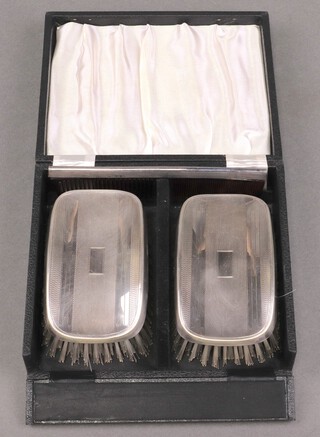 A pair of silver military backed hair brushes with engine turned decoration Birmingham 1947 and a silver comb, Birmingham 1948, cased 