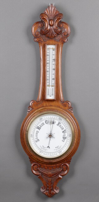 An aneroid wheel barometer and thermometer with porcelain dial, contained in an carved oak case 90cm  